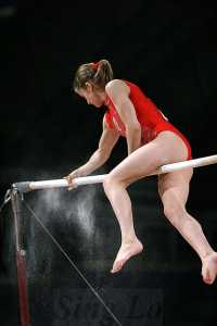 Gymnast preparing high bar with sandpaper